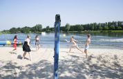 Gruppe spielt Beachvolleyball am Sandstrand mit See im Vakantiepark Klein Strand, Westflandern, Belgien.