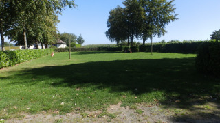 Grassy area with trees and hedges at Camping Um Bierg holiday park in Diekirch, Luxembourg.