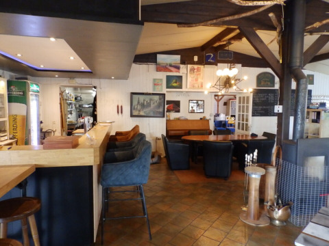 Intérieur d'un restaurant chaleureux à Camping Um Bierg, Diekirch, Luxembourg, avec bar et coin salon.