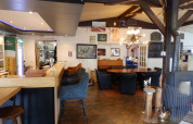Interno di un ristorante accogliente al Camping Um Bierg, Diekirch, Lussemburgo, con bar e area salotto.