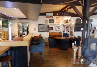 Interieur van een gezellig restaurant in Camping Um Bierg, Diekirch, Luxemburg, met bar en zitgedeelte.
