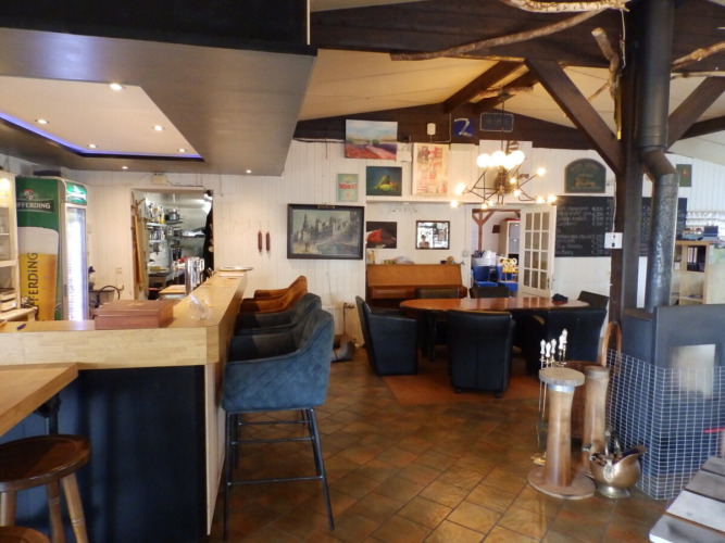 Binnenzicht van een gezellig restaurant bij Camping Um Bierg in Diekirch, Luxemburg met bar en zitplaatsen.