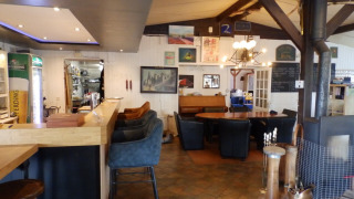Interior of a cozy restaurant at Camping Um Bierg, Diekirch, Luxembourg, featuring a bar and seating area.