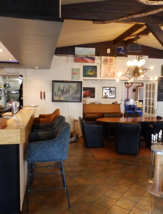 Interior de un restaurante acogedor en Camping Um Bierg, Diekirch, Luxemburgo, con barra y zona de asientos.