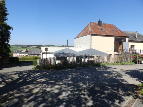 Vista en Camping Um Bierg en Diekirch, Luxemburgo, con casas, sombrillas y paisaje campestre en verano.