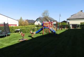 Aire de jeux avec toboggan, trampoline et balançoires sous le soleil au Camping Um Bierg, Diekirch, Luxembourg.