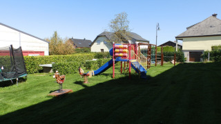 Playground with slide, trampoline, and swings on a sunny day at Camping Um Bierg, Diekirch, Luxembourg.