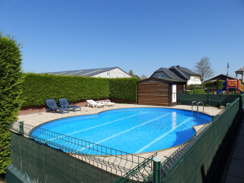 Piscina exterior con tumbonas y zona de juegos en Camping Um Bierg, un parque vacacional en Diekirch, Luxemburgo.