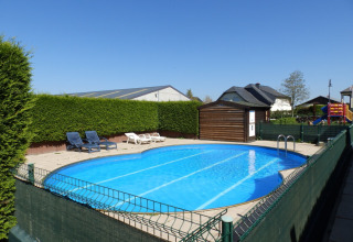 Udendørs swimmingpool med liggestole og legeområde på Camping Um Bierg feriepark i Diekirch, Luxembourg.