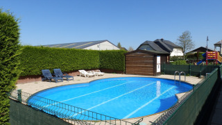 Outdoor swimming pool with sun loungers and playground at Camping Um Bierg holiday park in Diekirch, Luxembourg.