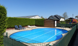 Piscina exterior con tumbonas y zona de juegos en Camping Um Bierg, un parque vacacional en Diekirch, Luxemburgo.