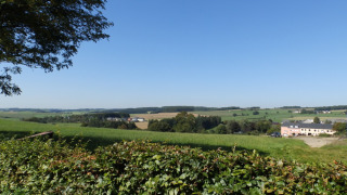 Uitzicht op het Luxemburgse platteland vanaf Camping Um Bierg vakantiepark in Diekirch onder een blauwe lucht.