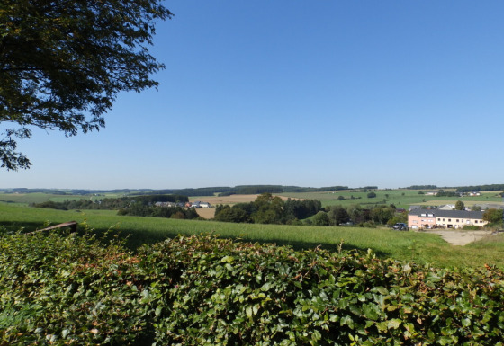 Vue sur la campagne luxembourgeoise depuis le parc de vacances Camping Um Bierg à Diekirch sous un ciel bleu.