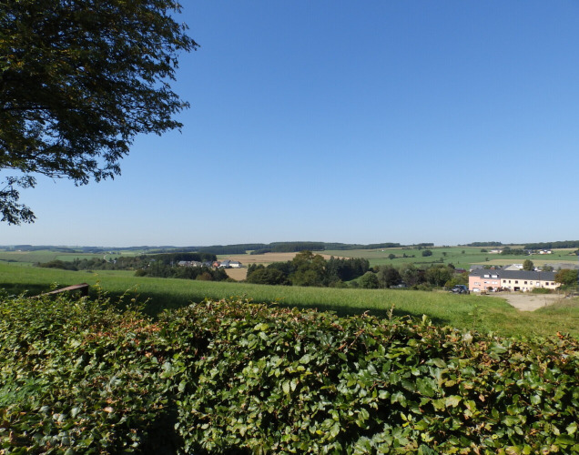 Uitzicht op het Luxemburgse platteland vanaf Camping Um Bierg vakantiepark in Diekirch onder een blauwe lucht.