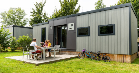 Familia disfruta de una comida al aire libre en Taos XL Delux Mobile Home, Baalse Hei, Bélgica, con bicicletas.