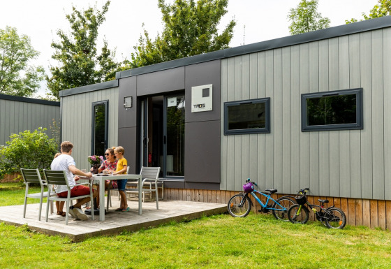 Familia disfruta de una comida al aire libre en Taos XL Delux Mobile Home, Baalse Hei, Bélgica, con bicicletas.