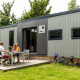 Familie nyder måltid udenfor Taos XL Delux Mobile home lodge ved Baalse Hei i Belgien, omgivet af cykler.