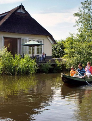 Familia navegando en bote junto a una casa pintoresca cerca de Sevenum, Limburg, Países Bajos.