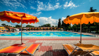 Piscine extérieure avec transats et parasols colorés à Campeggio Gasparina, Vénétie, Italie.