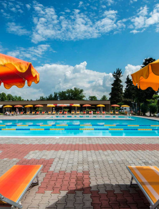 Piscina al aire libre con tumbonas y sombrillas coloridas en Campeggio Gasparina, Véneto, Italia.