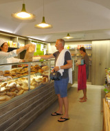 En bagerbutik på Camping Delle Rose i Ligurien, Italien, med kunder og brød på disken.