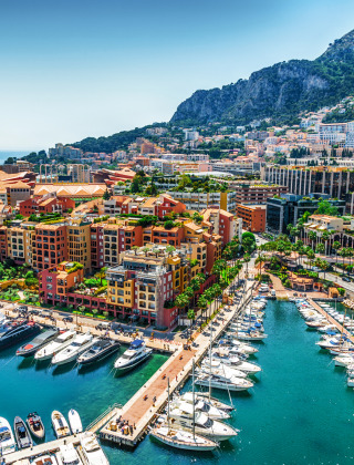 Puerto pintoresco con yates de lujo, edificios coloridos y montañas, probablemente en Liguria, Italia.