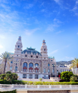 Elegante edificio histórico rodeado de palmeras y cielo azul, fotografiado cerca de Isolabona, Liguria, Italia.