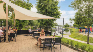 Terraza al aire libre en MarinaPark Bad Nederrijn, con vistas al puerto deportivo y un parque infantil en Gelderland.