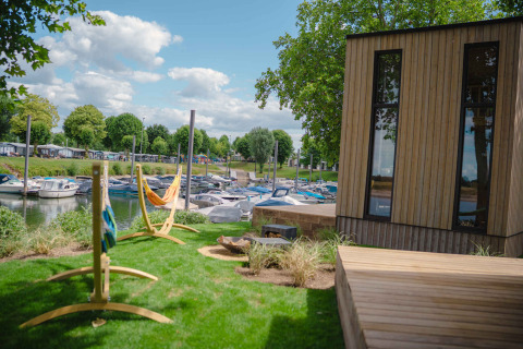 Cabaña de madera y hamacas con vistas a barcos atracados en MarinaPark Bad Nederrijn, Gelderland, Países Bajos.