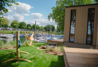 Houten huis en hangmatten met zicht op boten in MarinaPark Bad Nederrijn, vakantiepark in Gelderland.