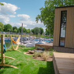 Cabaña de madera y hamacas con vistas a barcos atracados en MarinaPark Bad Nederrijn, Gelderland, Países Bajos.
