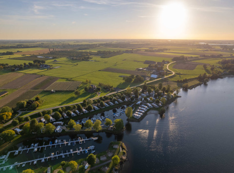 Luftfoto af MarinaPark Bad Nederrijn i Gelderland, Holland, med både, hytter og grønne marker i solskin
