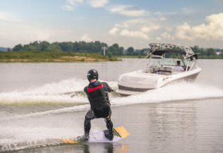 Person wakeboarder efter speedbåd på sø i MarinaPark Bad Nederrijn, feriepark i Gelderland, Holland.