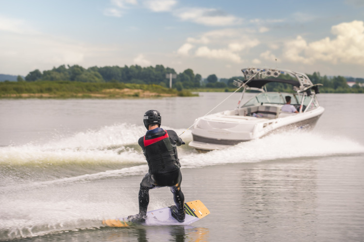 Mensch wakeboardet hinter Motorboot auf See im MarinaPark Bad Nederrijn, Ferienpark in Gelderland, Niederlande.