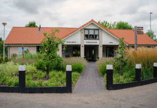 Toegang tot een vakantieparkgebouw met rood dak en tuin bij MarinaPark Bad Nederrijn in Gelderland, Nederland.