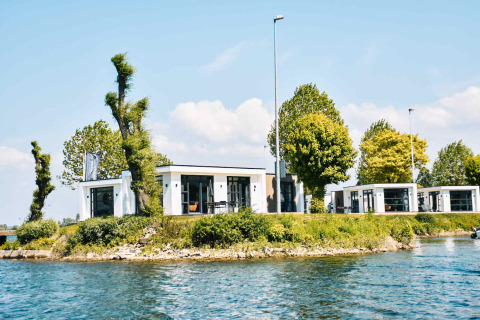 Casas vacacionales modernas junto al agua en MarinaPark Bad Nederrijn, rodeadas de árboles en Gelderland, Países Bajos.