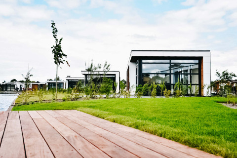 Casas de vacaciones modernas en MarinaPark Residentie Nieuw Loosdrecht junto a césped y agua en los Países Bajos.