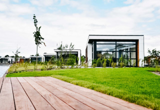 Casas de vacaciones modernas en MarinaPark Residentie Nieuw Loosdrecht junto a césped y agua en los Países Bajos.