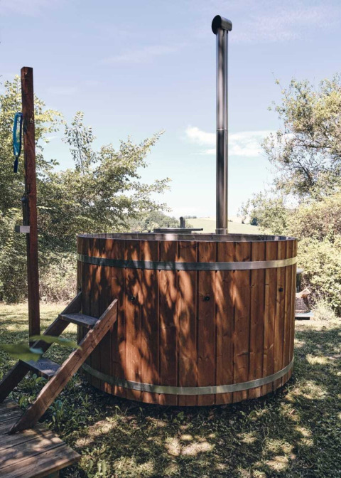 Bañera caliente de madera al aire libre en Camping d'Artagnan, Occitania, Francia, rodeada de naturaleza.