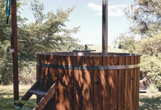 Vasca idromassaggio in legno all'aperto al Camping d'Artagnan in Occitania, Francia, immersa nel verde.
