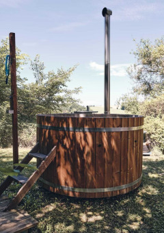 Bain nordique en bois à l'extérieur au Camping d'Artagnan en Occitanie, France, entouré de verdure.