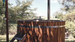 Bain nordique en bois à l'extérieur au Camping d'Artagnan en Occitanie, France, entouré de verdure.