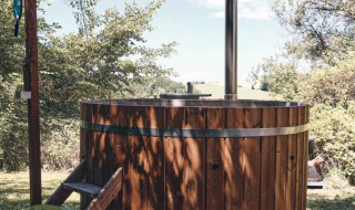 Bain nordique en bois à l'extérieur au Camping d'Artagnan en Occitanie, France, entouré de verdure.