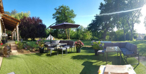 Gemütlicher Gartenbereich mit Sitzgruppen und Sonnenschirm im Ferienpark Camping d'Artagnan, Occitanie, Frankreich.