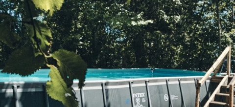 Piscina fuori terra con scala in legno tra gli alberi al Camping d'Artagnan, Occitania, Francia.
