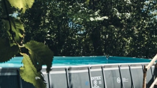 Piscine hors-sol avec escalier en bois entourée d’arbres au Camping d'Artagnan, Occitanie, France.