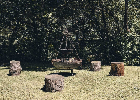 Braciere all'aperto con ceppi d'albero come sedute al Camping d'Artagnan, Occitania, Francia.