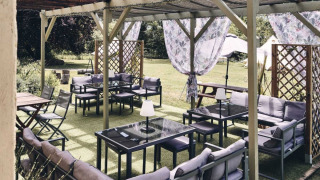 Aire de détente extérieure du Camping d'Artagnan, Occitanie, France, avec canapés, tables et voilages.