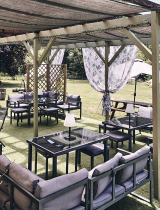 Aire de détente extérieure du Camping d'Artagnan, Occitanie, France, avec canapés, tables et voilages.