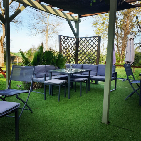 Gemütliche Sitzgruppe auf grüner Terrasse im Freien bei Camping d'Artagnan, Occitanie, Frankreich.